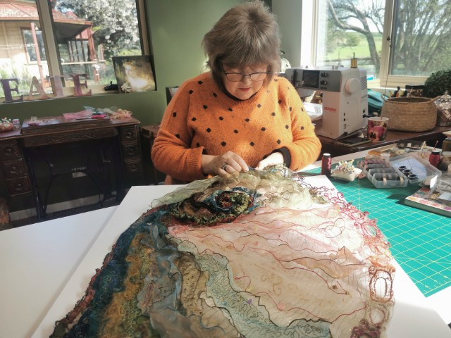 Image shows Cindy Thompson stitching her abalone shell for her Artist Profile with Art Trails Tasmania