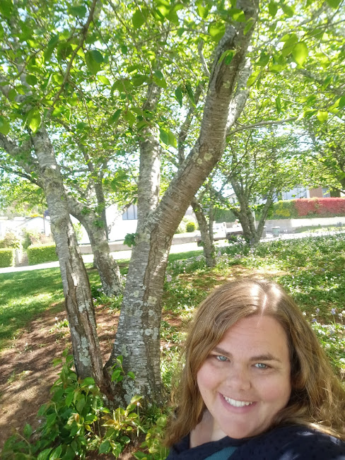 Image shows artist Emma Pilgrim in front of trees in her Artist Profile story with Art Trails Tasmania