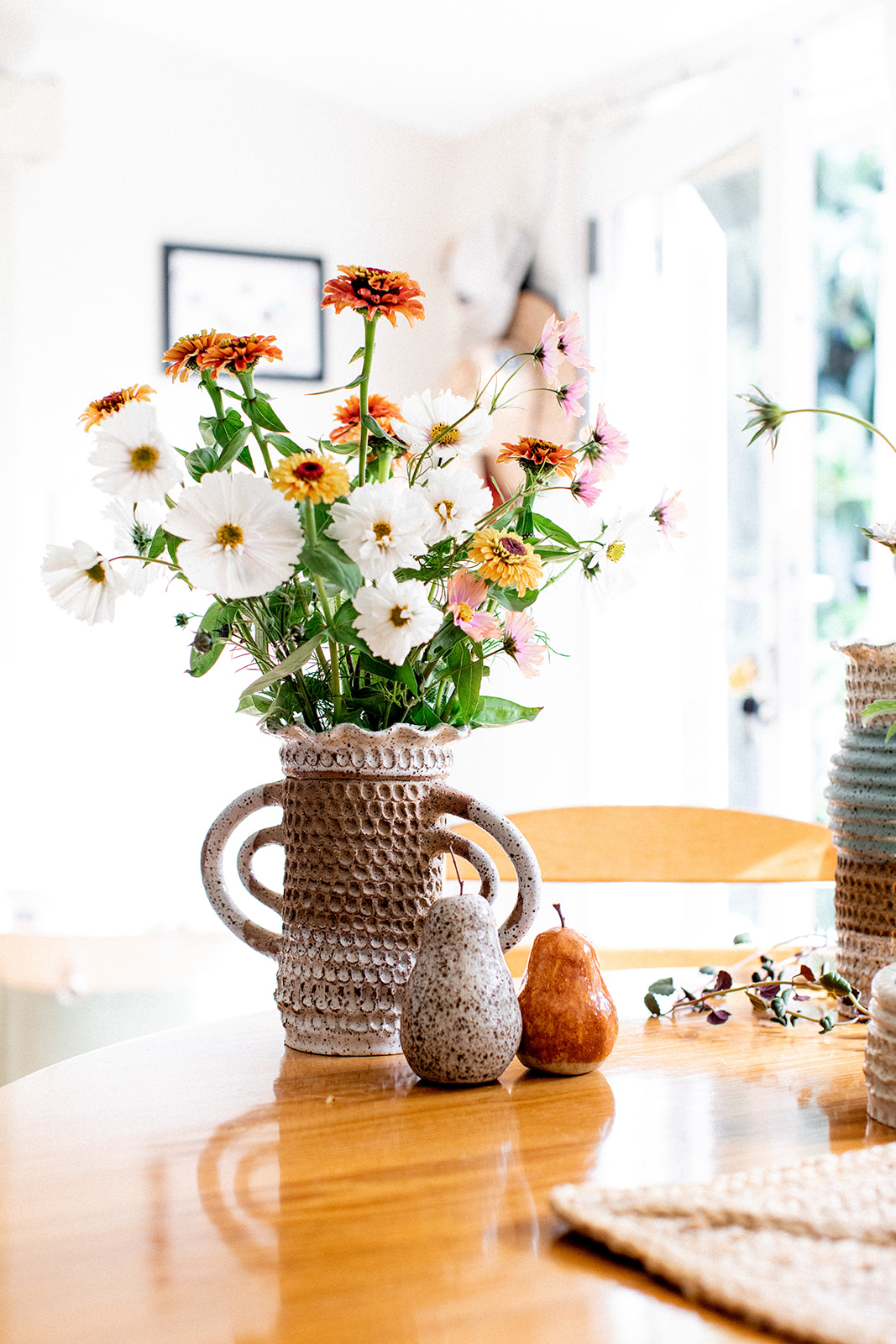 Image shows a vase with cosmos flowers and pears by Christie Lange in her Artist Profile Art Trails Tasmania