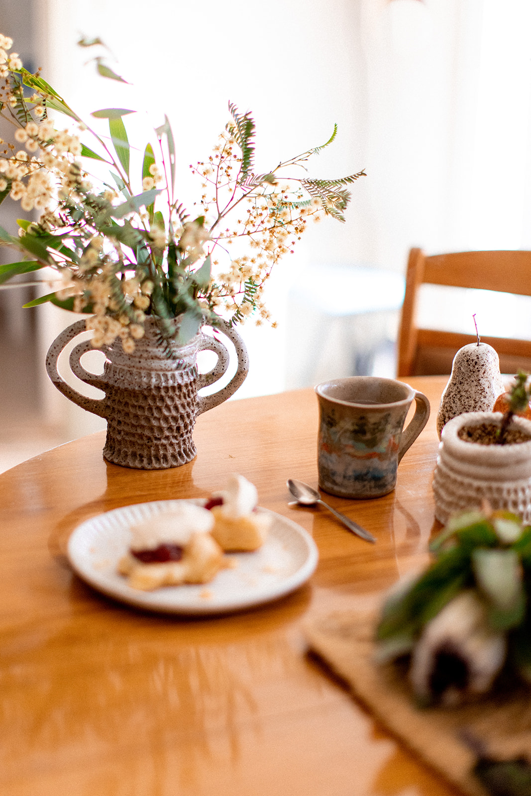 Image shows a ceramic vase with flowers with morning tea by Christie Lange in her Artist Profile Art Trails Tasmania