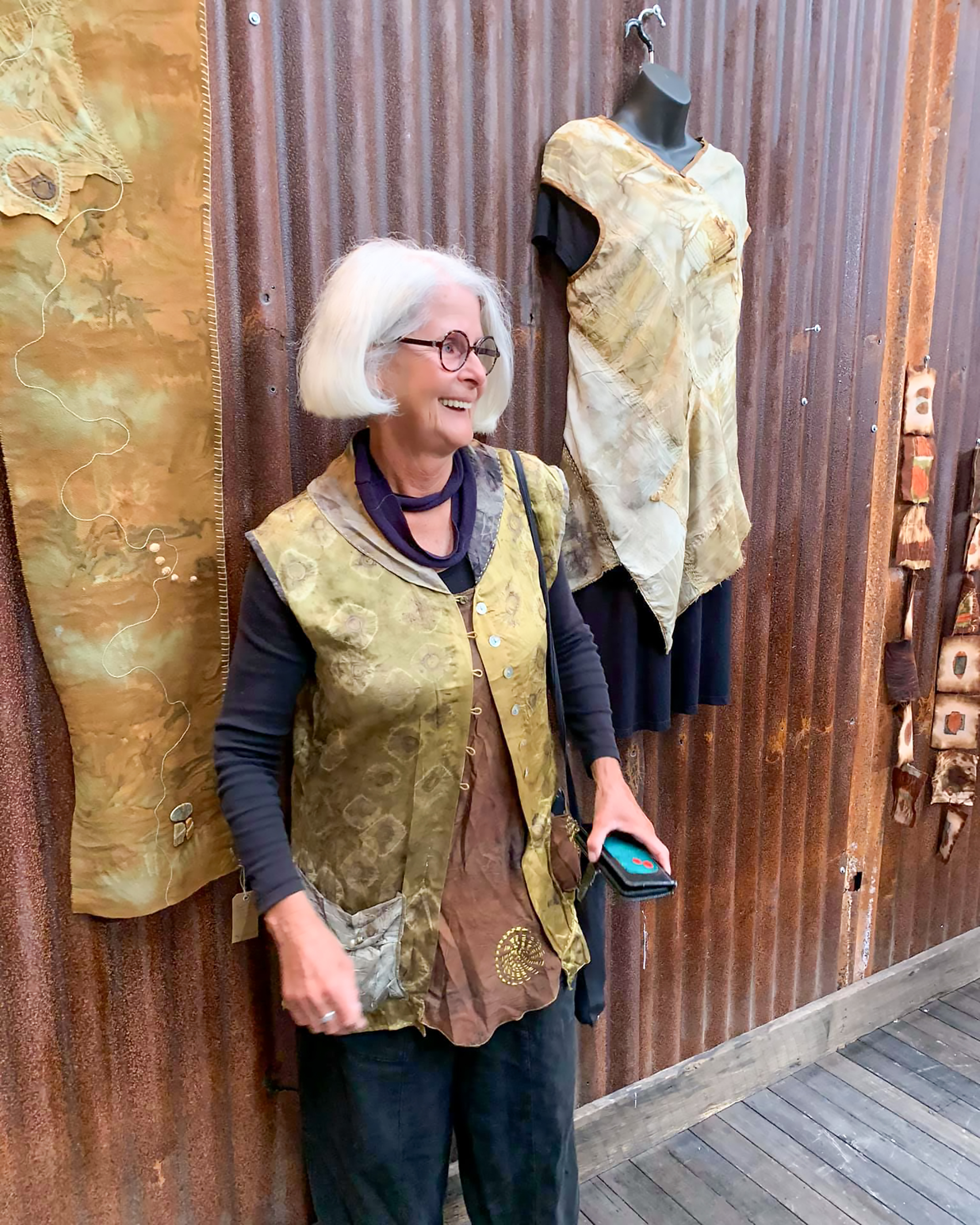 The image shows textile artist Aujke Boonstra in front of her eco-dyed fabrics for the Textile Art Retreat Found, Collected, Dyed, Stitched with Textile Artist Aujke Boonstra Art Trails Tasmania for her workshop at the Tin Dragon Trails Cottages