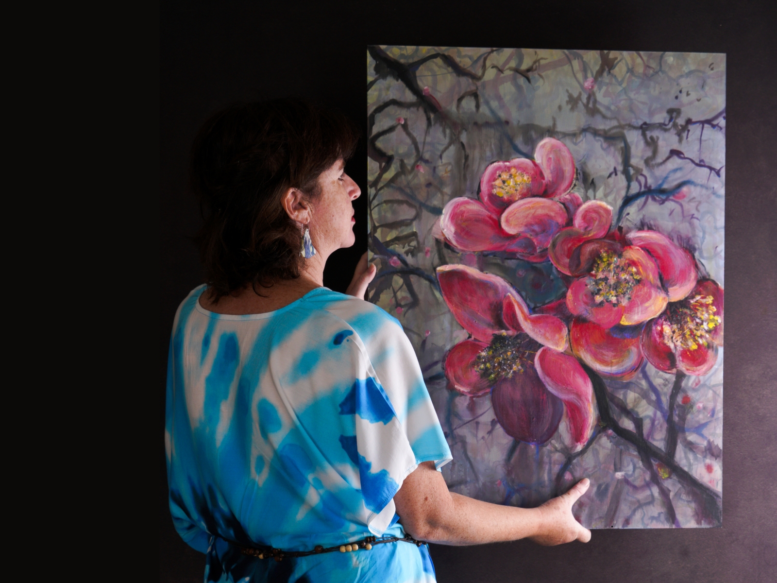Image shows the artist Lee-Anne Peters with her floral painting for her Exhibition News Lee-Anne Peters Solo Exhibition Initiation Into the Unknown Art Trails Tasmania