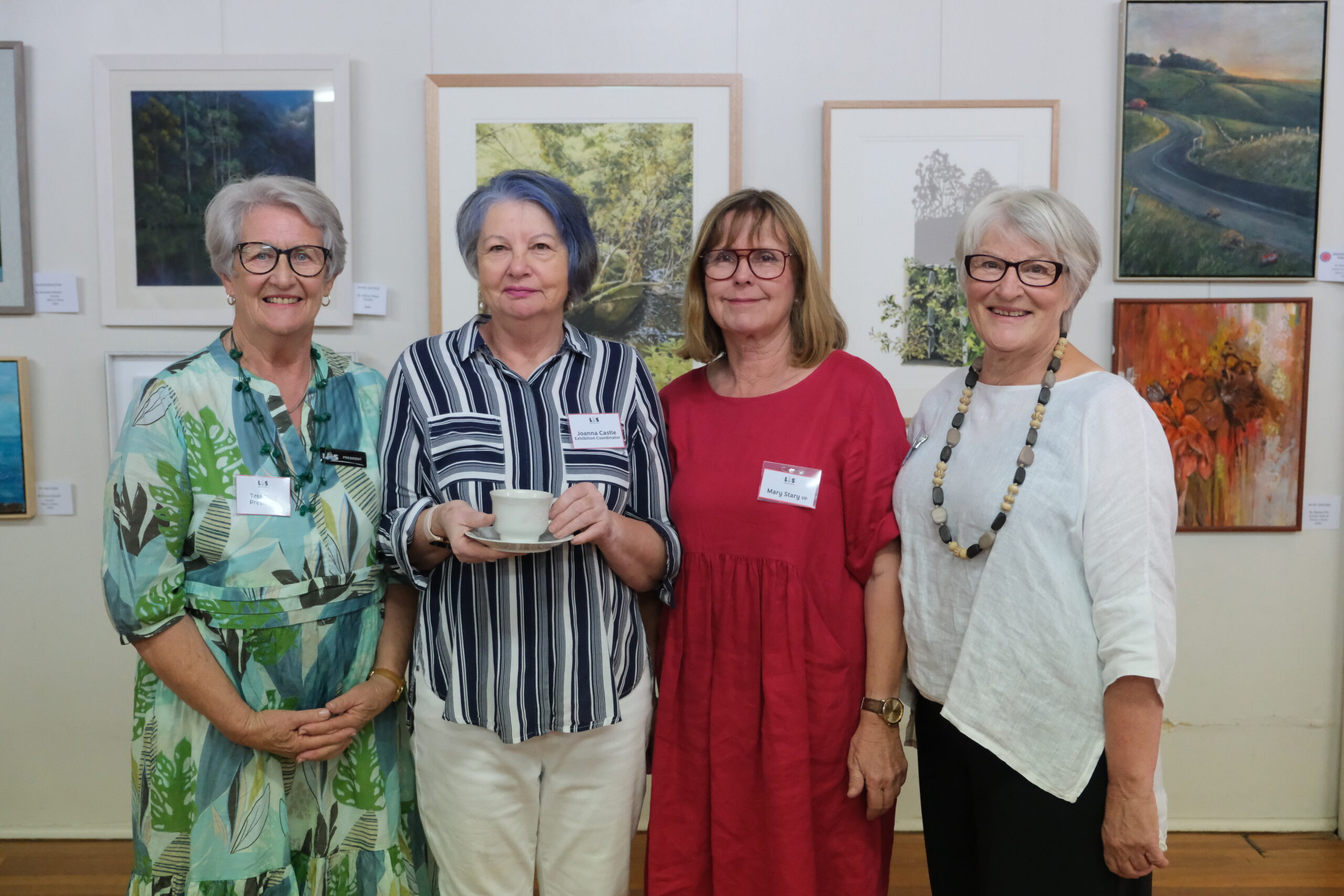 Image is of people at an art exhibition opening in front of paintings for the Art Society Profile Join the Launceston Art Society's Journey Through Education, Workshops and Exhibitions Art Trails Tasmania