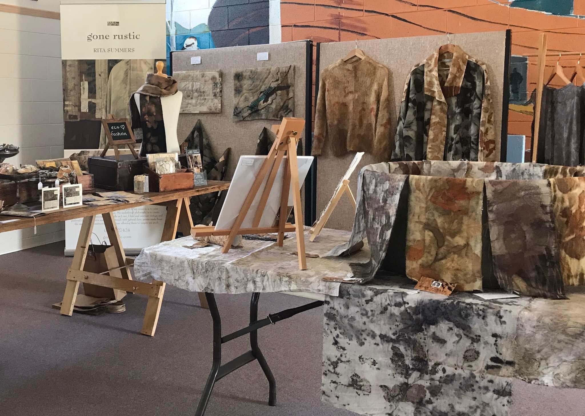 Image shows a collection of mixed media artworks in an art exhibition of eco dyed fabric slow stitched for the Artist Profile of Renowned Nature Inspired Textile Artist Rita Summers in her Art Trails Tasmania story